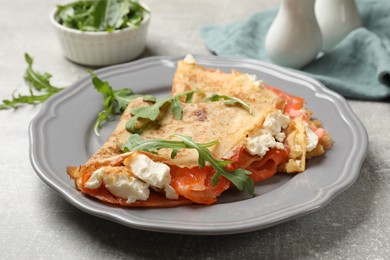 Photo of Delicious crepes with salmon, cream cheese and arugula on grey table, closeup