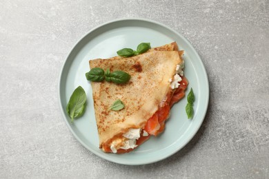 Photo of Delicious crepe with salmon, cream cheese and basil on grey table, top view