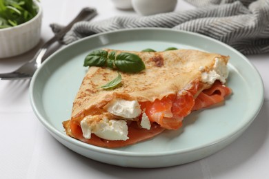 Photo of Delicious crepe with salmon, cream cheese and basil on white table, closeup