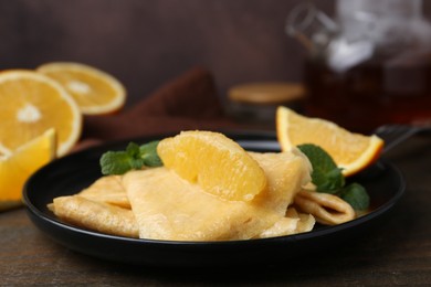 Photo of Delicious Crepes Suzette served on wooden table, closeup