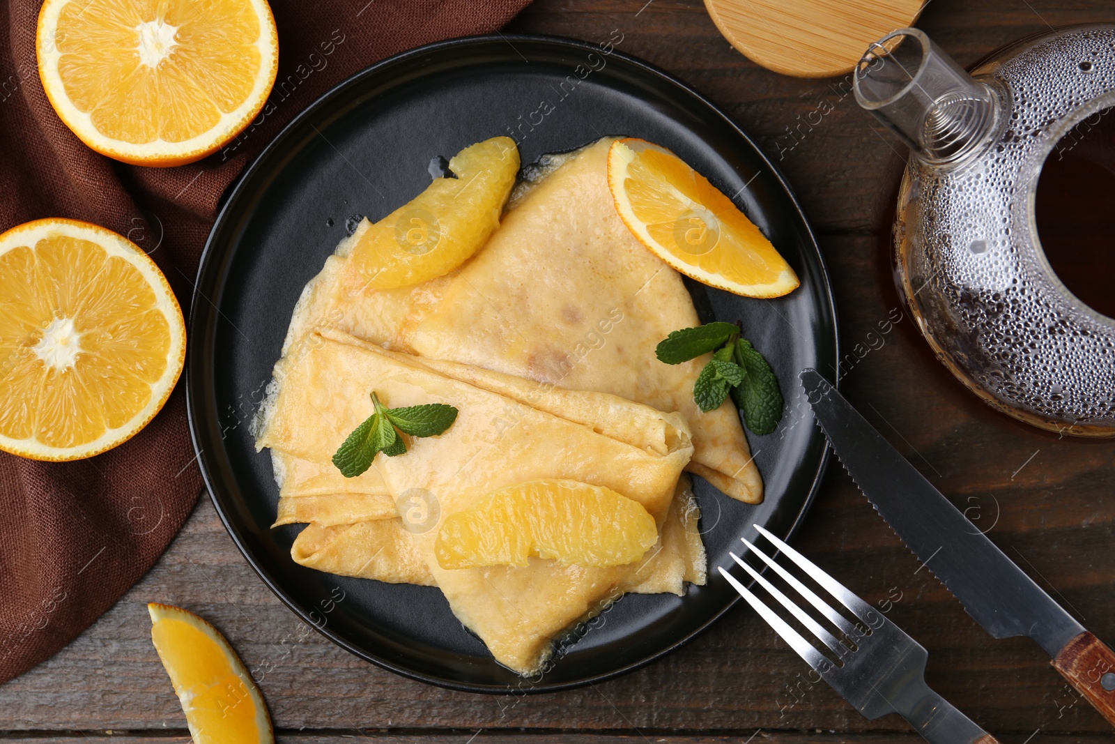 Photo of Delicious Crepes Suzette served on wooden table, flat lay