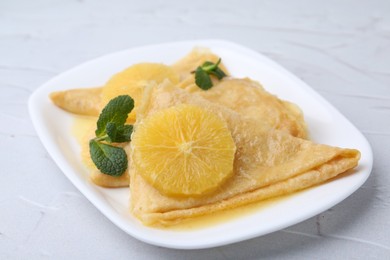 Photo of Delicious Crepes Suzette on white textured table, closeup