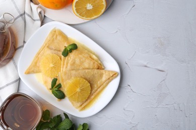 Photo of Delicious Crepes Suzette served on white textured table, flat lay. Space for text