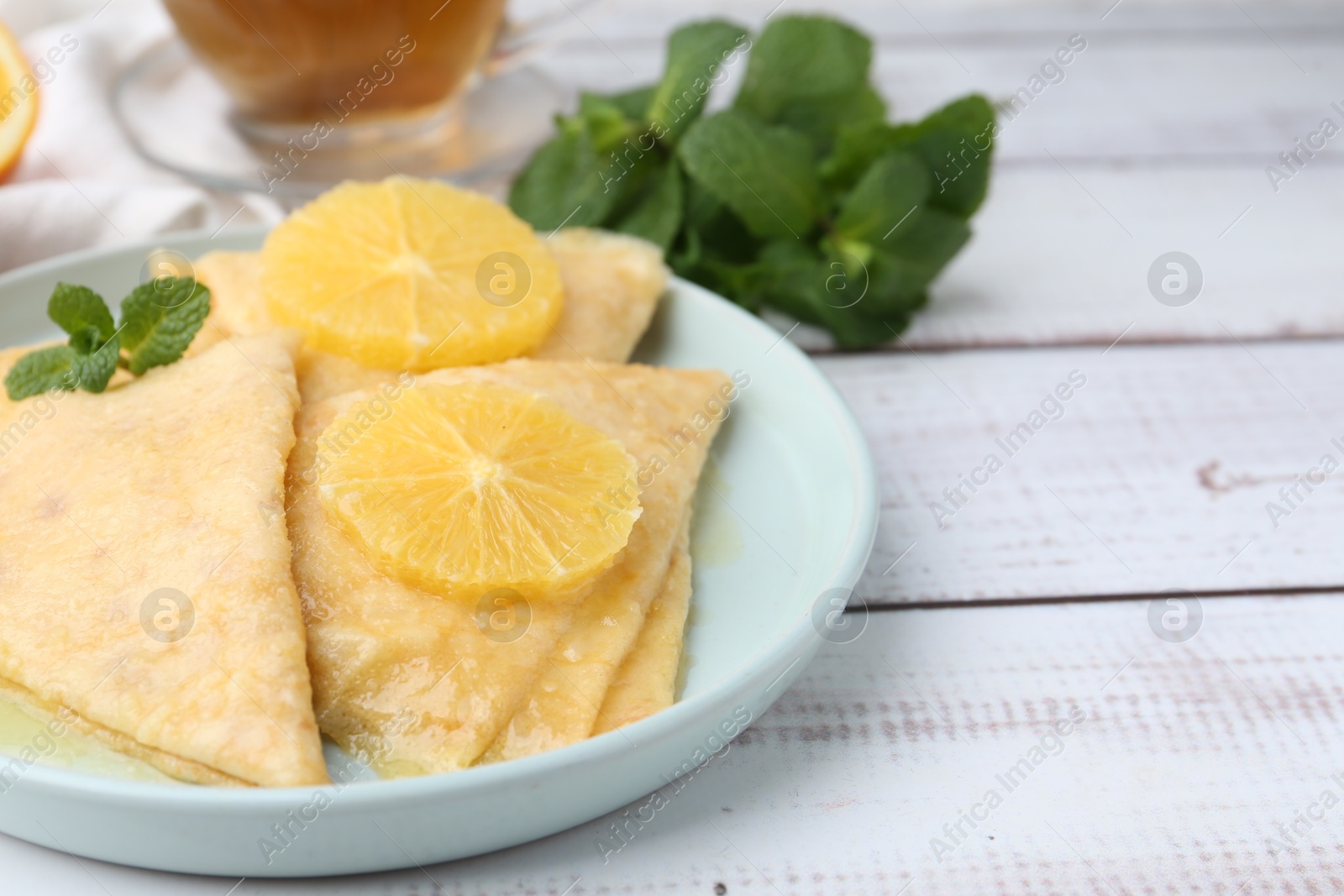 Photo of Delicious Crepes Suzette on white wooden table, closeup. Space for text