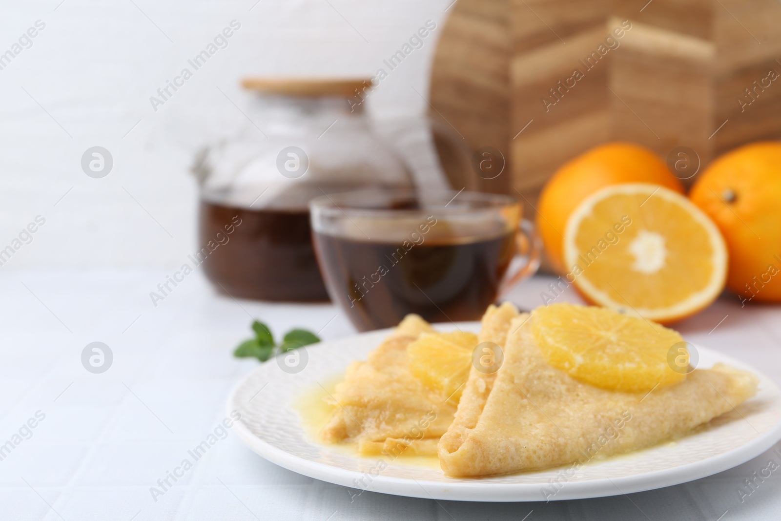 Photo of Delicious Crepes Suzette served on white tiled table, closeup