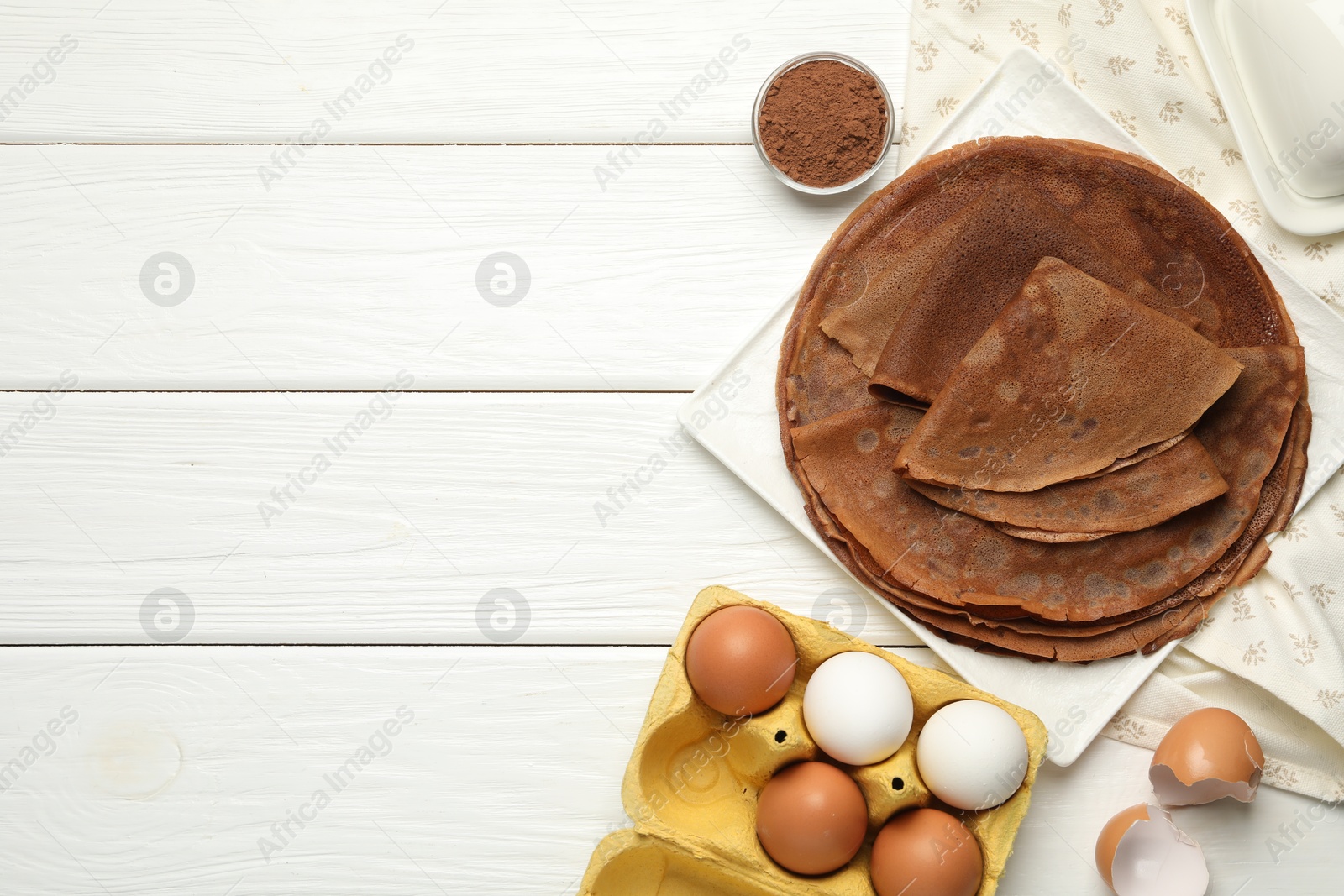 Photo of Delicious chocolate crepes and ingredients on white wooden table, flat lay. Space for text