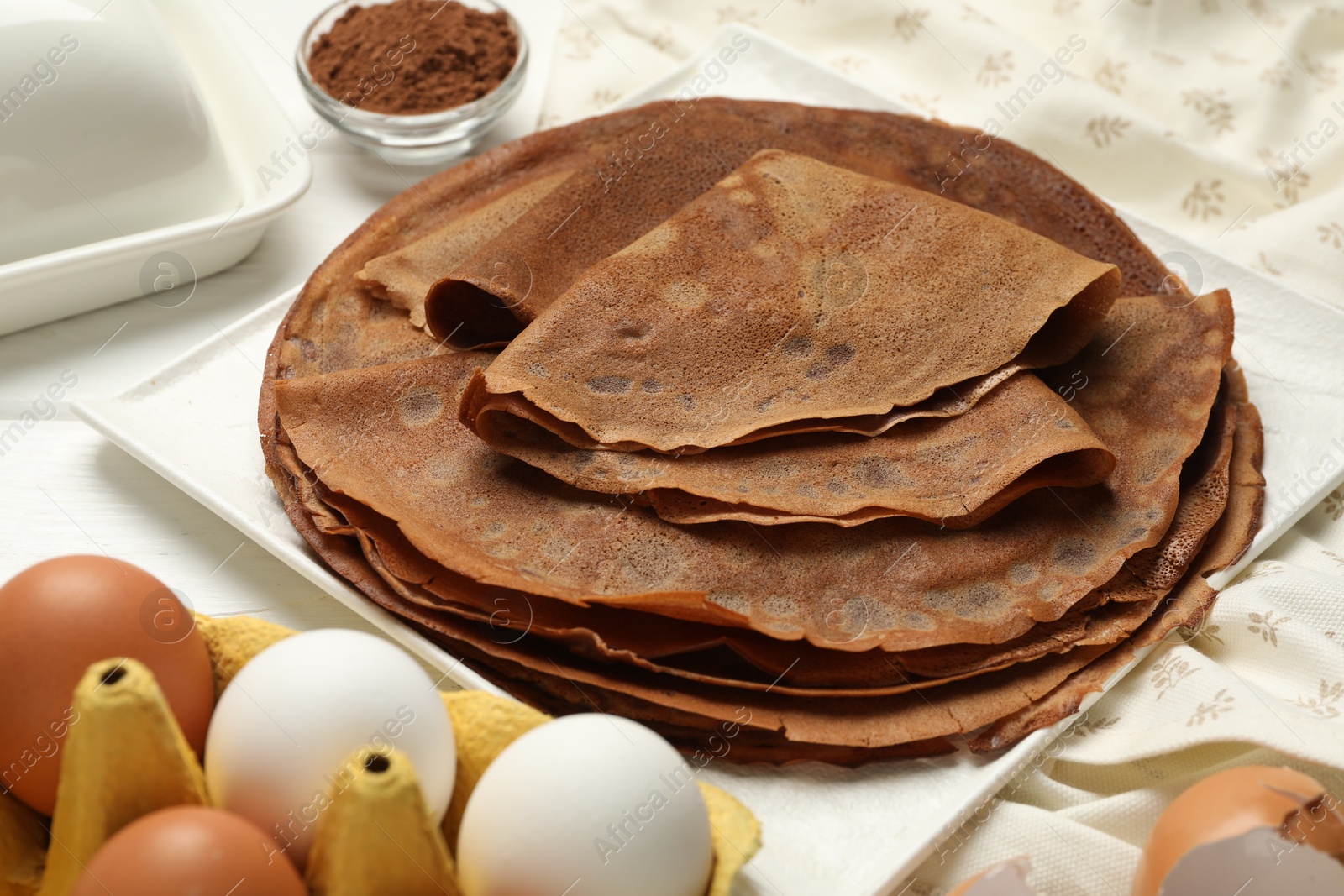 Photo of Delicious chocolate crepes and ingredients on white wooden table, closeup