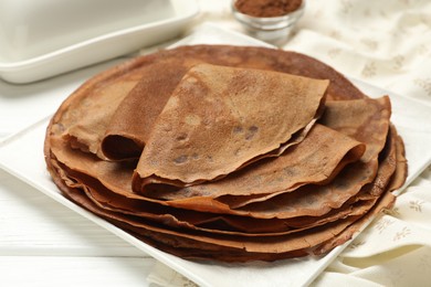 Photo of Delicious chocolate crepes on white wooden table, closeup