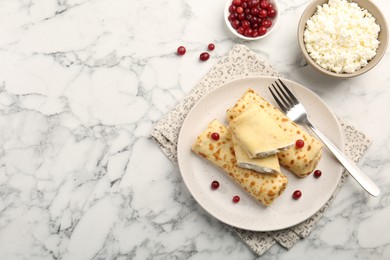 Photo of Delicious rolled crepes with cottage cheese, raisins and cranberries on white marble table, flat lay. Space for text