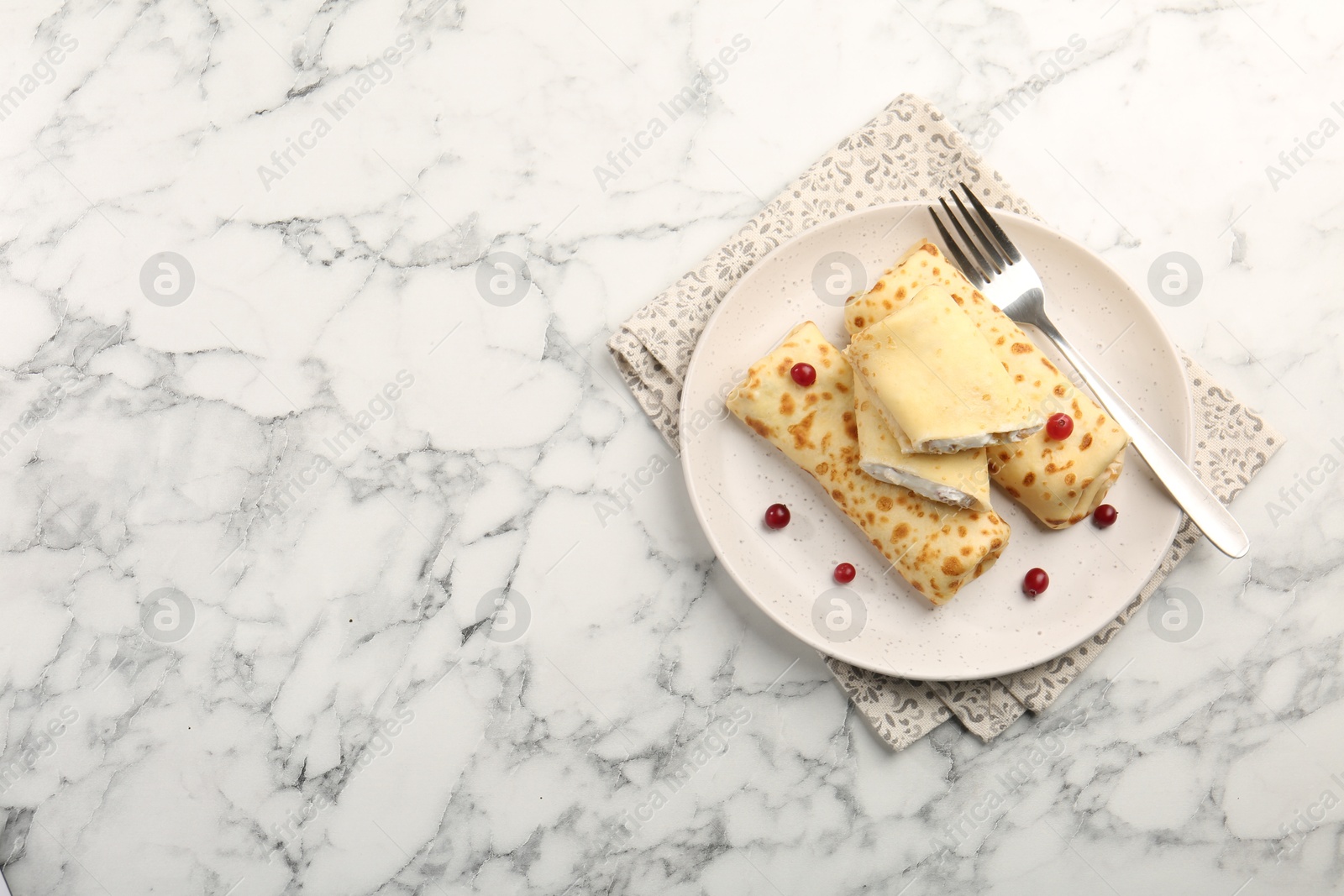 Photo of Delicious rolled crepes with cottage cheese, raisins and cranberries on white marble table, top view. Space for text