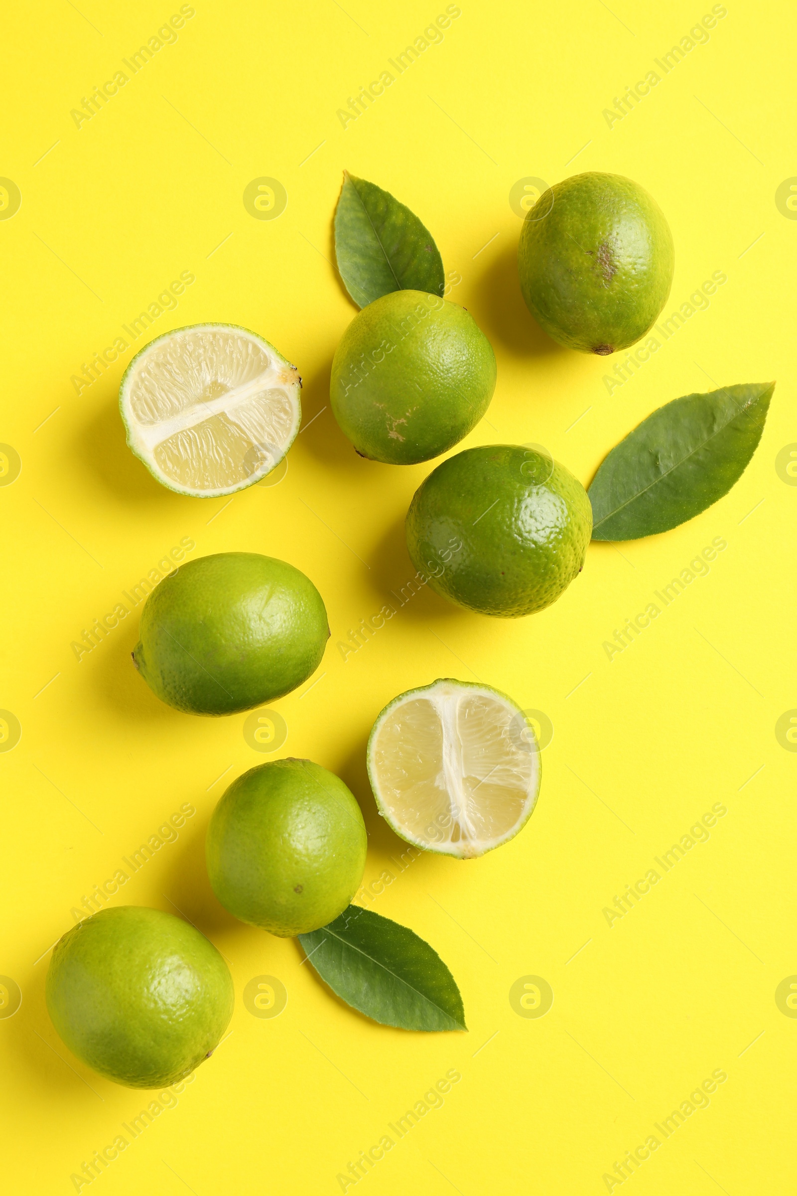 Photo of Fresh limes and leaves on yellow background