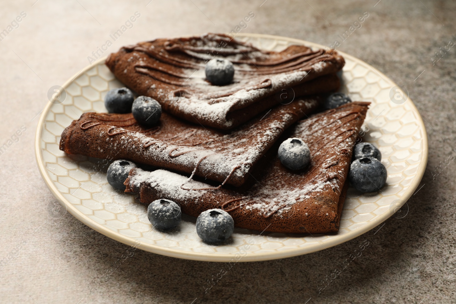 Photo of Delicious chocolate crepes with blueberries on grey table, closeup