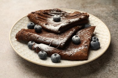 Photo of Delicious chocolate crepes with blueberries on grey table, closeup