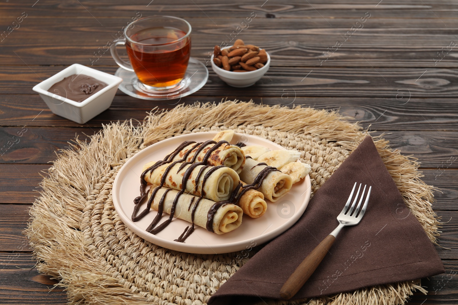 Photo of Delicious crepes with chocolate sauce served on wooden table