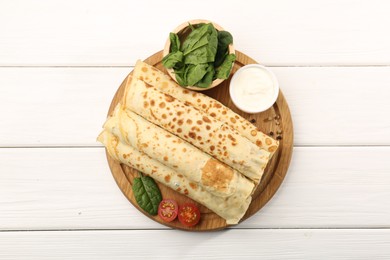 Photo of Tasty rolled crepes with cottage cheese and spinach served on white wooden table, top view