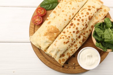 Photo of Tasty rolled crepes with cottage cheese and spinach served on white wooden table, top view