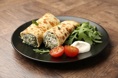 Photo of Tasty rolled crepes with cottage cheese and spinach served on wooden table, closeup