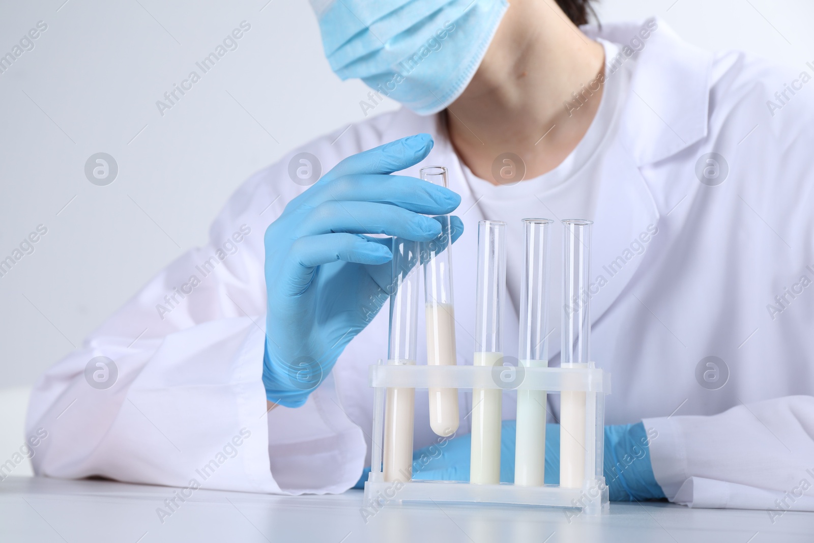 Photo of Laboratory testing. Scientist working with test tubes at white table, closeup