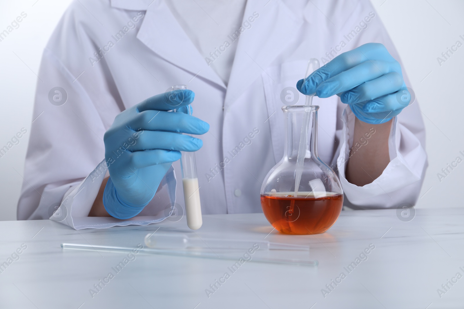 Photo of Laboratory testing. Scientist working with glassware at white marble table, closeup