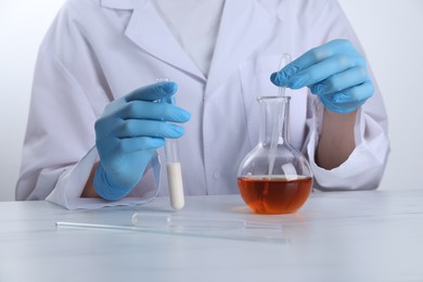 Laboratory testing. Scientist working with glassware at white marble table, closeup