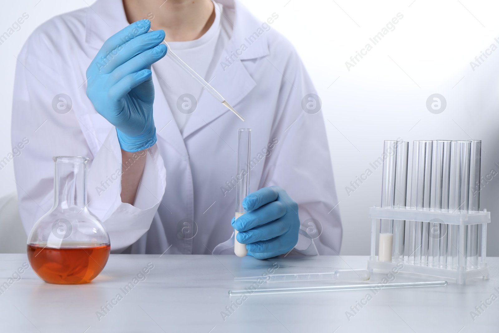 Photo of Laboratory testing. Scientist working with glassware at white marble table, closeup