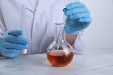 Photo of Laboratory testing. Scientist working with glassware at white marble table, closeup