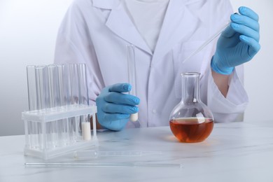 Photo of Laboratory testing. Scientist working with glassware at white marble table, closeup