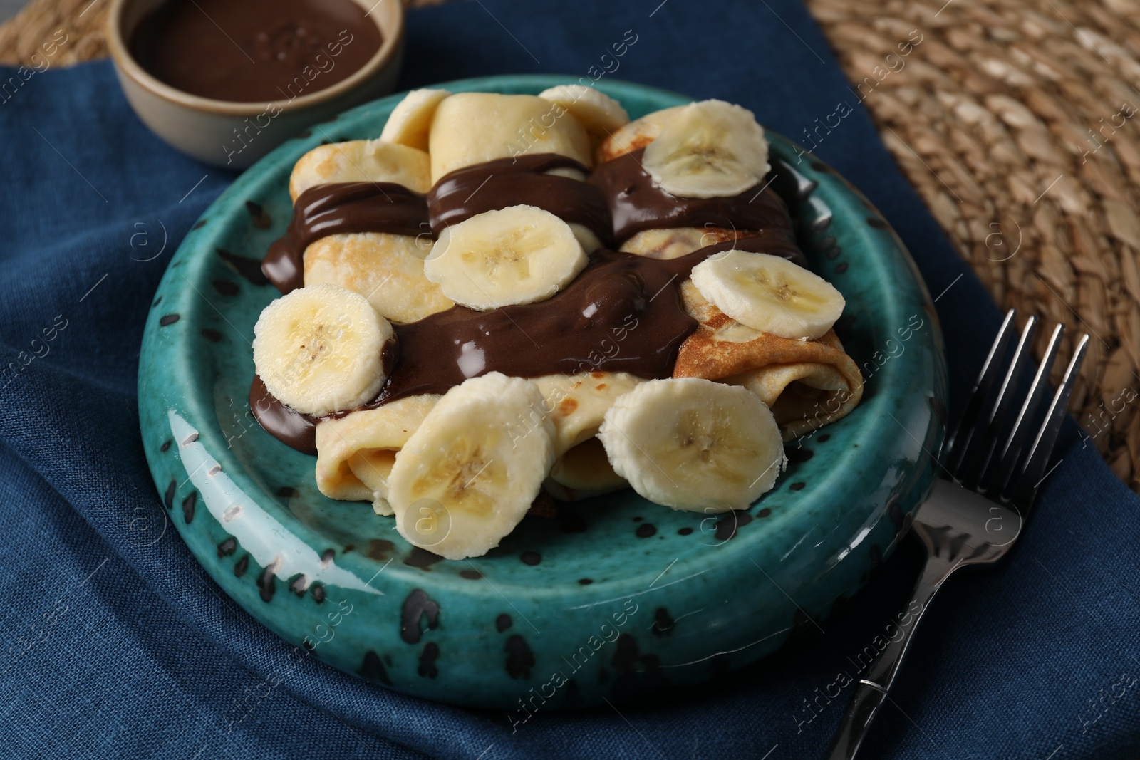 Photo of Delicious crepes with banana and chocolate paste on table, closeup