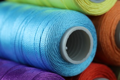 Photo of Spools of colorful sewing threads as background, closeup