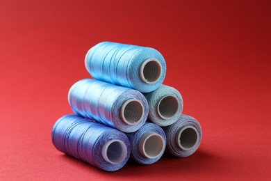 Photo of Spools of colorful sewing threads on red background