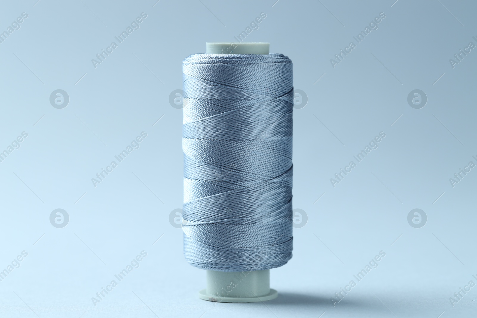 Photo of Spool of colorful sewing thread on light background