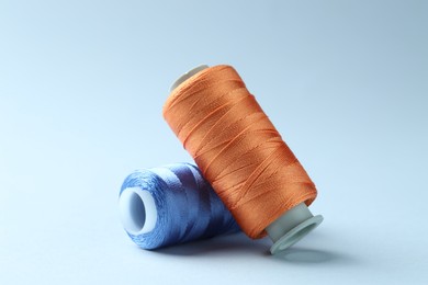 Photo of Spools of colorful sewing threads on light background