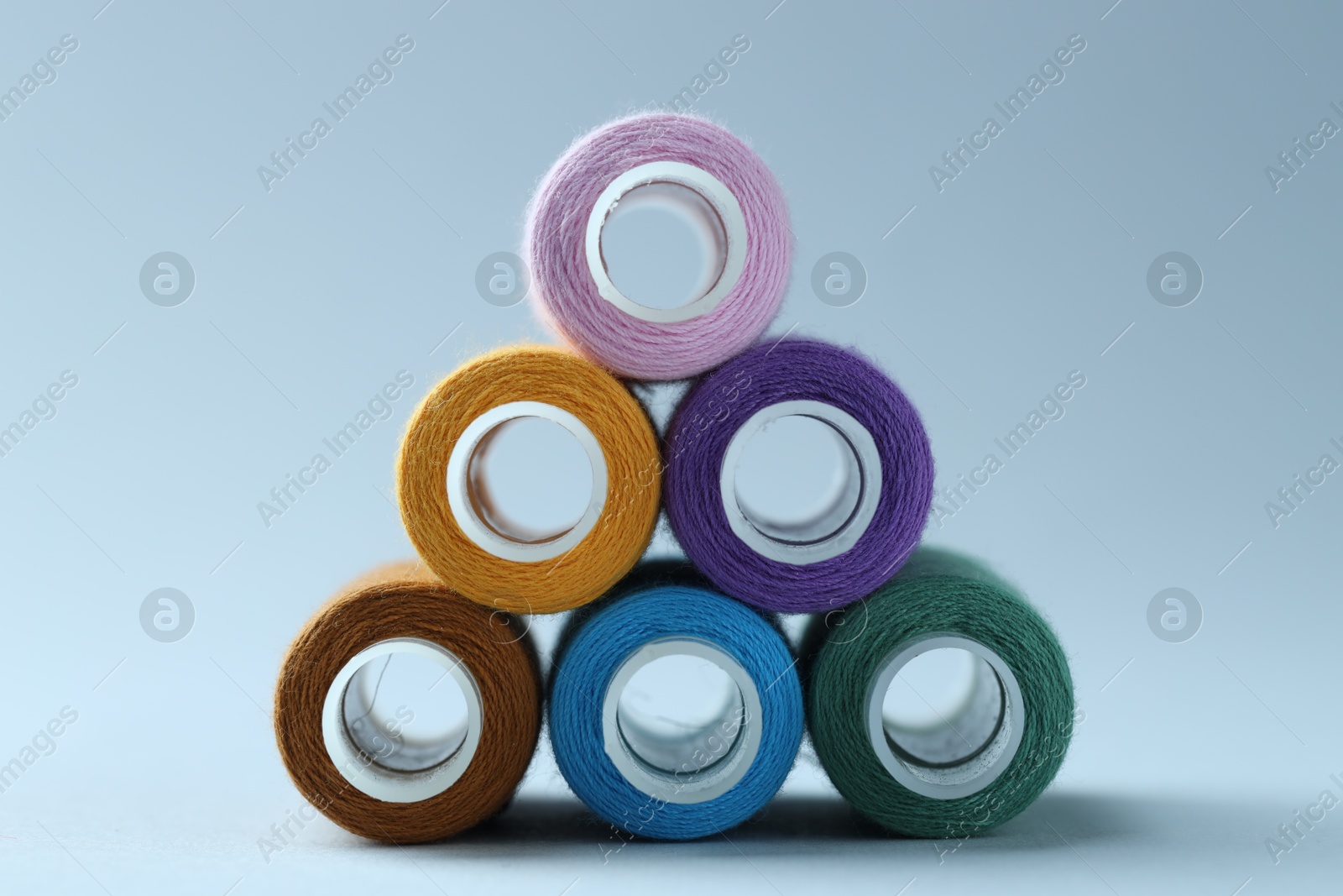 Photo of Spools of colorful sewing threads on light background