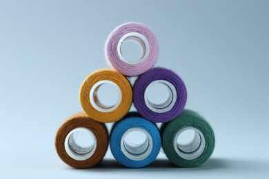 Photo of Spools of colorful sewing threads on light background