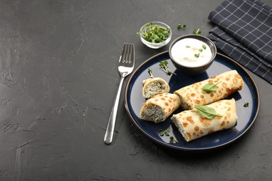 Photo of Delicious crepes with cottage cheese, spinach and sour cream served on black table. Space for text