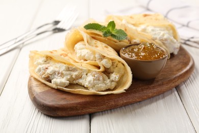 Photo of Delicious crepes with cottage cheese, jam and mint on white wooden table, closeup