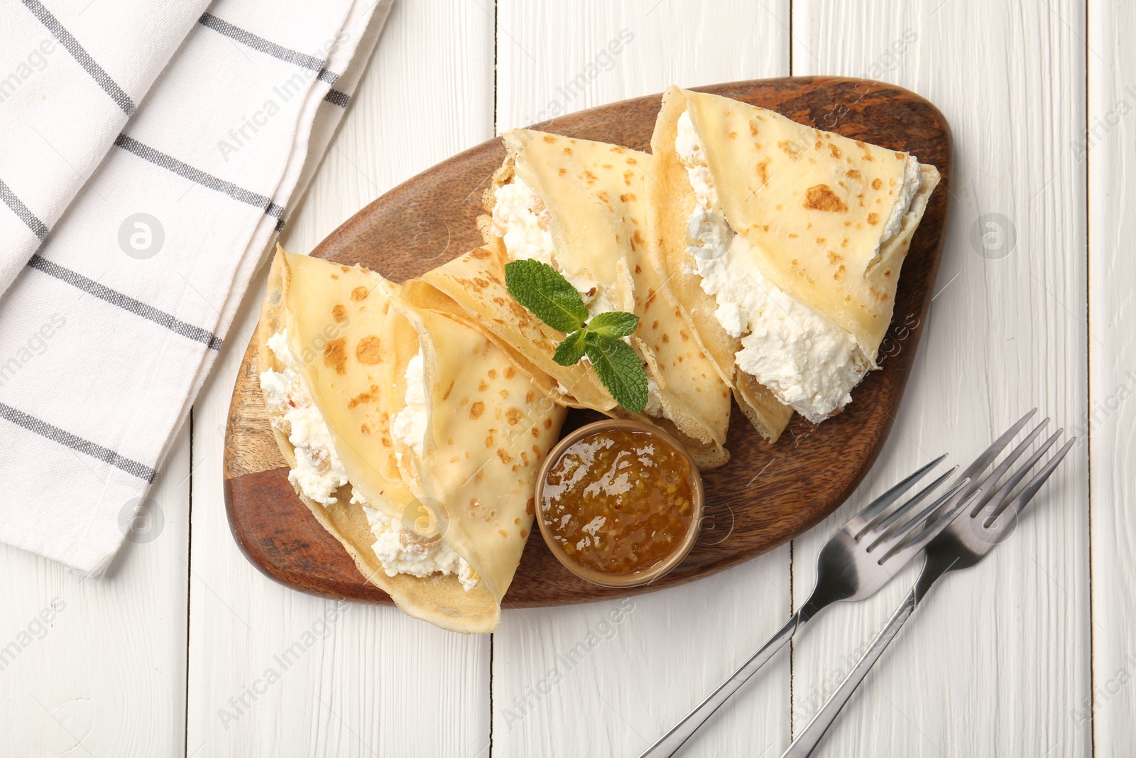 Photo of Delicious crepes with cottage cheese, jam and mint served on white wooden table, top view