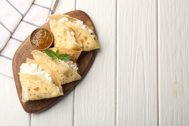 Photo of Delicious crepes with cottage cheese, jam and mint on white wooden table, top view. Space for text