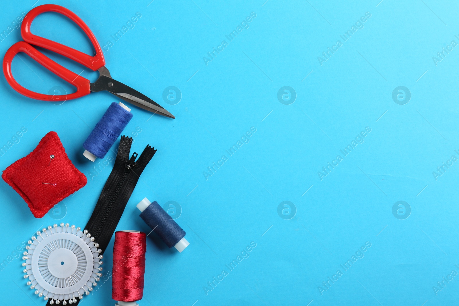 Photo of Different sewing supplies on light blue background, flat lay. Space for text