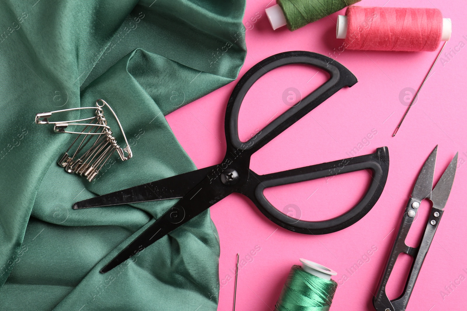 Photo of Different sewing supplies on pink background, flat lay