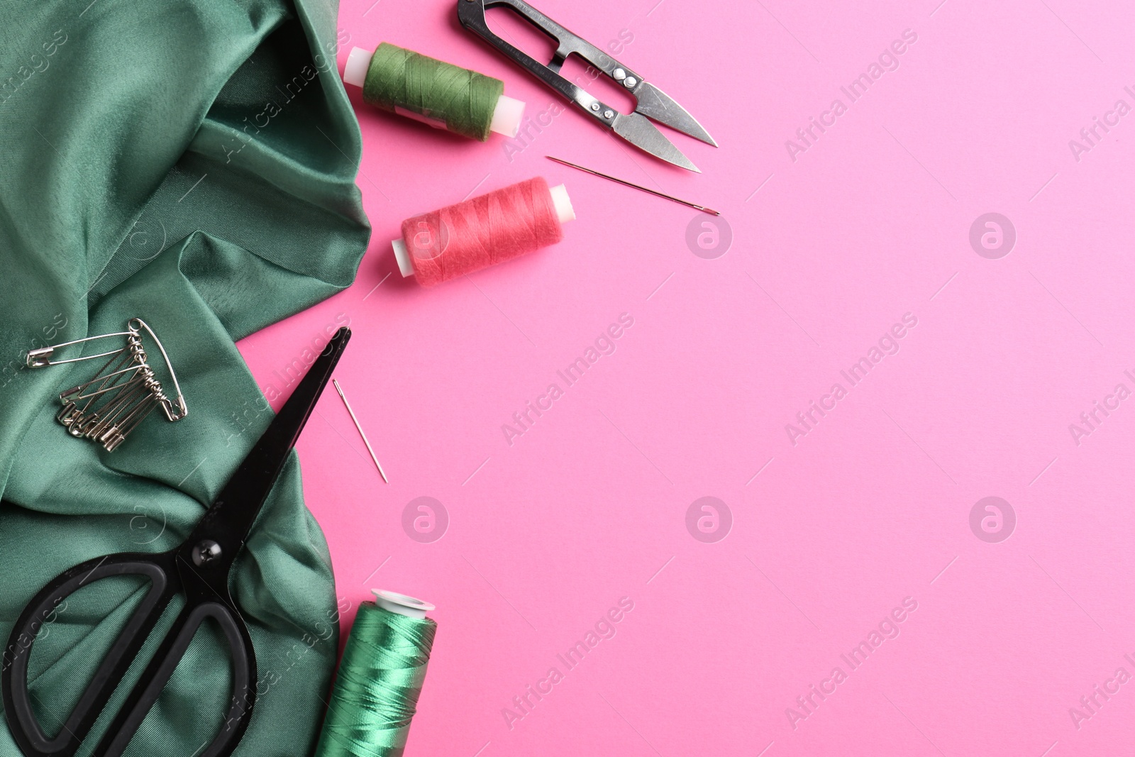 Photo of Different sewing supplies on pink background, flat lay. Space for text