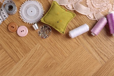 Photo of Sewing threads and other supplies on wooden table, flat lay. Space for text