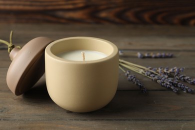 Photo of Soy wax candle, lid and lavender flowers on wooden table, space for text