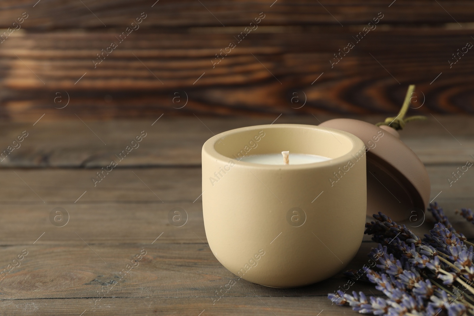 Photo of Soy wax candle, lid and lavender flowers on wooden table, space for text