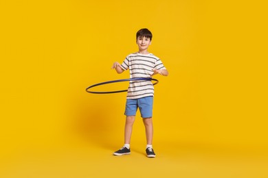 Photo of Boy exercising with hula hoop on yellow background