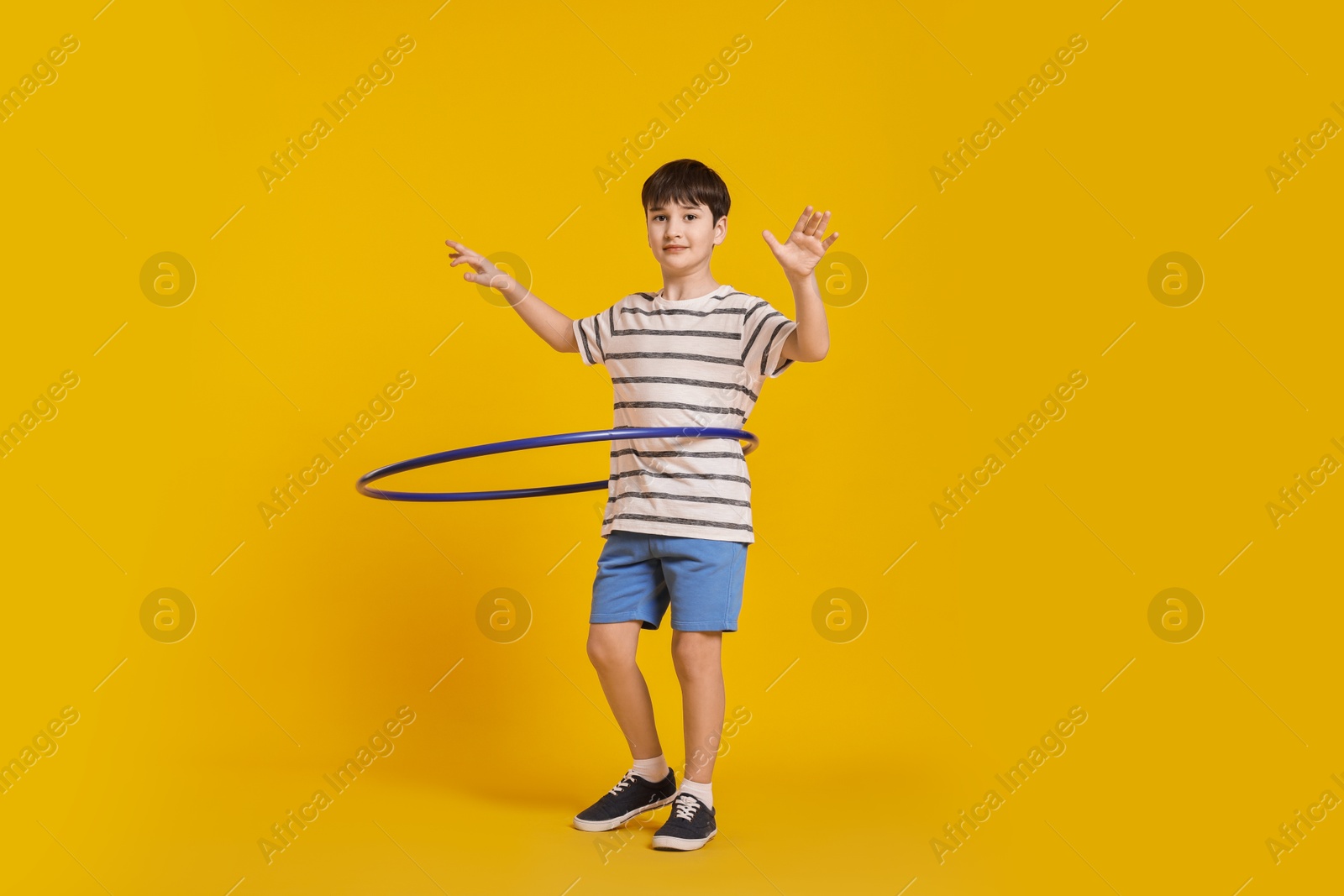 Photo of Boy exercising with hula hoop on yellow background