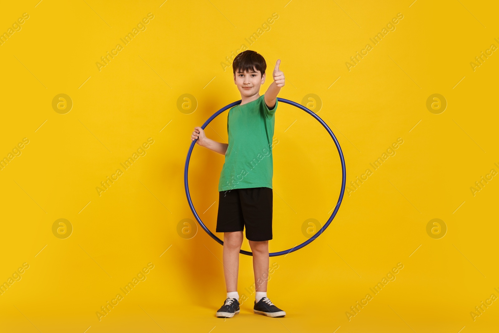 Photo of Boy with hula hoop showing thumbs up on yellow background