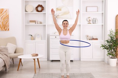 Photo of Smiling woman training with hula hoop at home