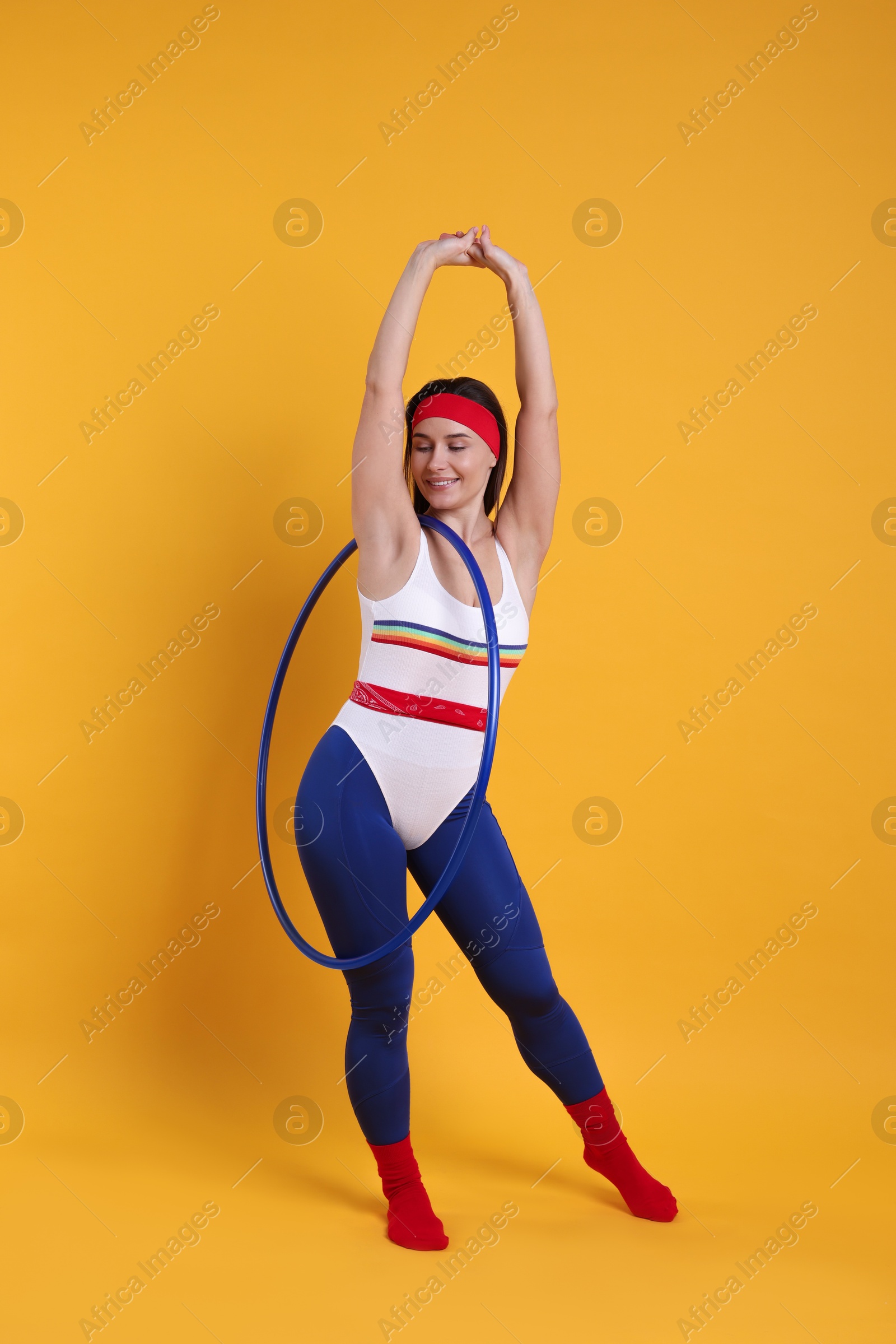 Photo of Smiling woman with hula hoop on orange background