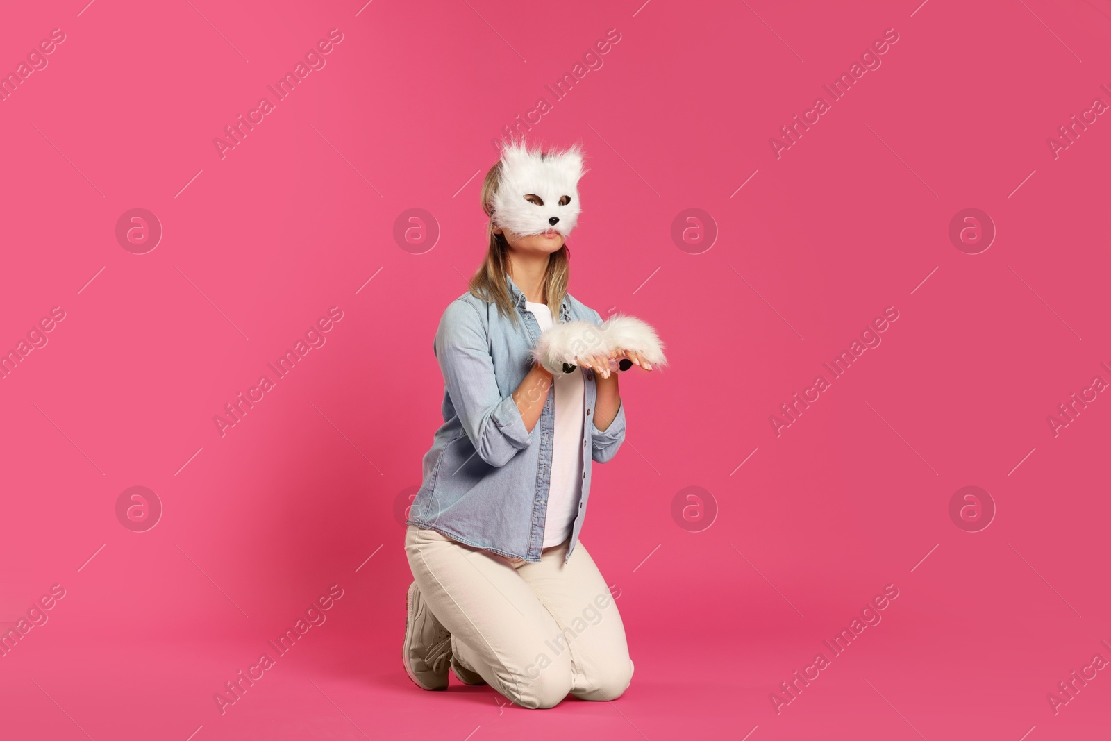 Photo of Quadrobics. Woman wearing cat mask and gloves on pink background